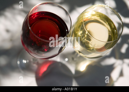 Red and White wine in tall glasses, on table cloth under tree shadow Stock Photo