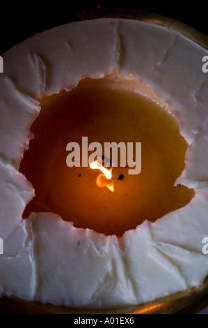 Burning candle at Druk Thubten Sangag Choeling monastery, a Drukpa Kagyu site in Darjeeling, India. Top-down view of flickering flame and melted wax. Stock Photo