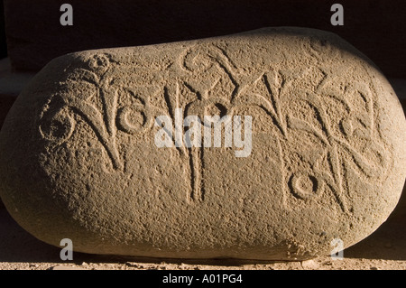 A side-lit mani stone featuring ancient carved inscriptions against a dark background in Leh town, Ladakh, India. Stock Photo