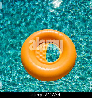 Orange inflatable ring floats in a blue swimming pool casting a shadow Stock Photo