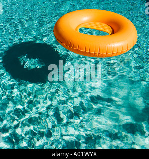 Orange inflatable ring floats in a blue swimming pool casting a Stock ...