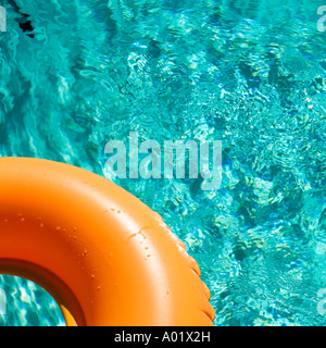 Orange inflatable ring floats in a blue swimming pool casting a shadow Stock Photo