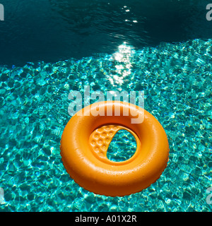 Orange inflatable ring floats in a blue swimming pool casting a shadow Stock Photo