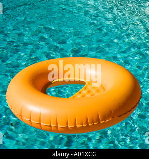 Orange inflatable ring floats in a blue swimming pool casting a shadow Stock Photo