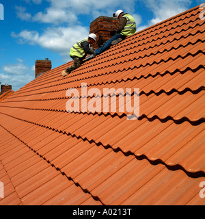 Roofing tilers lay tiles on a roof Stock Photo