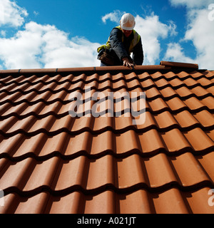 Roof tiler lays tiles on a new house england No release required, features of face totally hidden man is unrecognizable Stock Photo