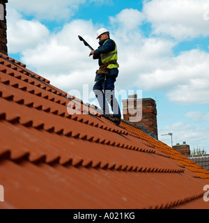 Roof tiler standing on top of new house. Stock Photo