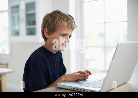 Boy using laptop in dining room Stock Photo