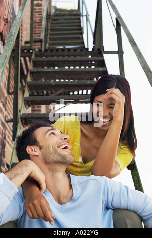 Couple sitting on fire escape stairs Stock Photo