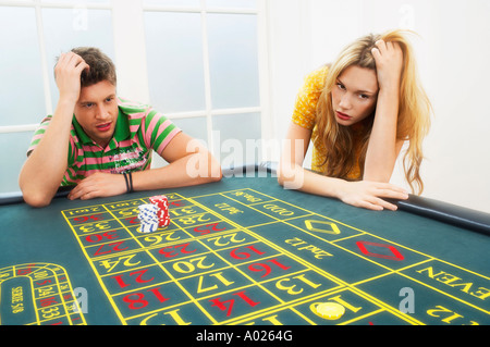Young man and woman losing on roulette table Stock Photo