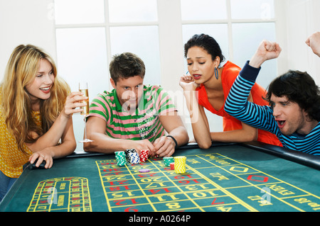 Young man winning on roulette table while friends lose Stock Photo