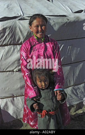 Young woman in Mongolian national clothes called as del and little girl near traditional dwelling ger or yurt. North Mongolia Stock Photo