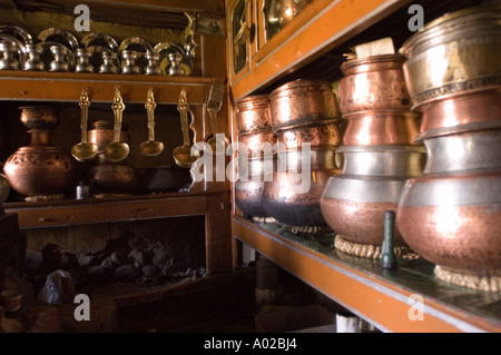 Traditional brass pots and utensils in the interior of a Ladakhi kitchen, Ladakh, India. Authentic copper cookware displayed on wooden shelves. Stock Photo
