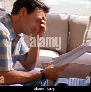 Caucasian executive working from home with laptop and paperwork Stock Photo