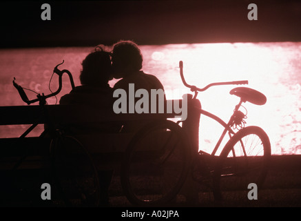 Silhouette couple kissing on park bench Stock Photo