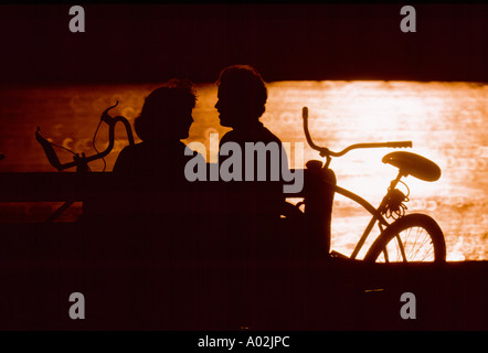 Silhouette couple sitting on park bench Stock Photo