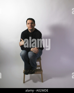 Man on stool looking candid and defensive and yet confident air Stock Photo