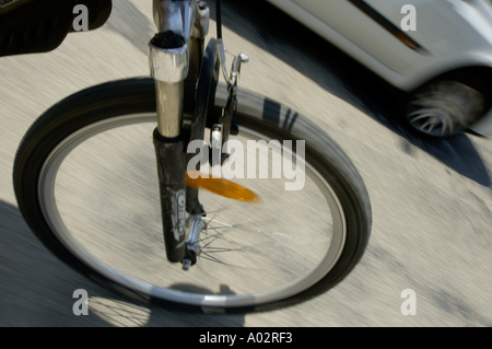 Blurred front wheel of a speeding mountain bike on a road Stock Photo