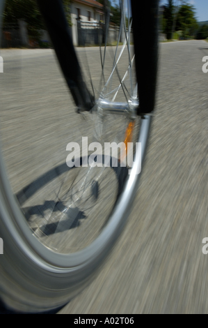 Blurred front wheel of a speeding mountain bike on a road Stock Photo