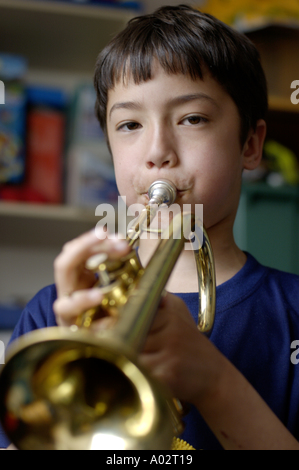 Young boy breathing into a saxophone in his bedroom Stock Photo