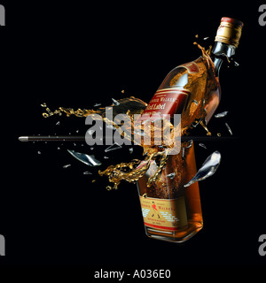 whiskey bottle breaked by a bullet with splash Stock Photo