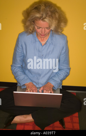Woman sitting on floor with laptop Stock Photo