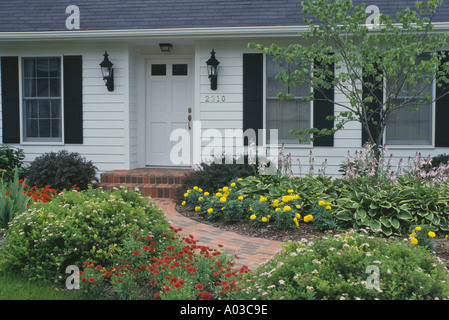 Front entrance to house via brick path through blooming flowers, Missouri USA Stock Photo