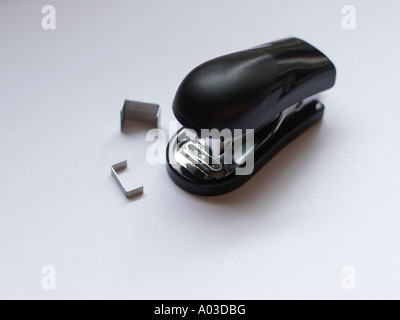 Small black stapler and staples on a white surface. Stock Photo