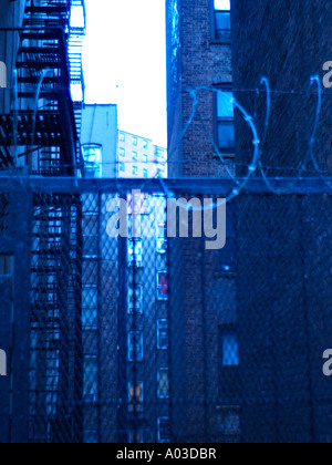 Coils of barbed wire atop a wrought iron fence in front of an alleyway on the upper west side of New York City. Stock Photo