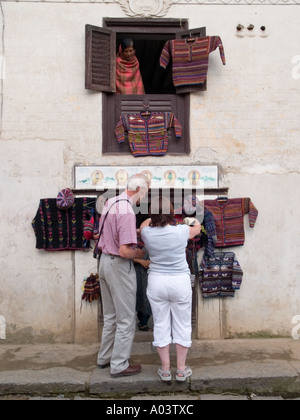 TOURISTS at WOOLLENS SHOP with hand knitted garments hanging outside Bungamati Kathmandu Valley Nepal Asia Stock Photo
