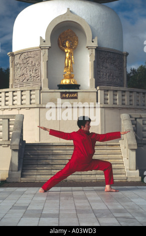 Carol Smith Yoga Teacher doing Surya Namaskar Sun Salutations in front of the Milton Keynes Buddhist Peace Pagoda Stock Photo