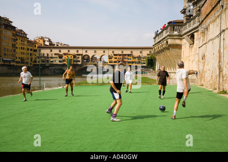 Group of Italian men playing soccer on bank of Arno River near the Ponte Vecchio Firenze Italy Stock Photo