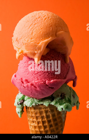 Three scoops of ice cream against orange background Stock Photo