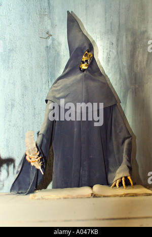 A Skeleton wearing a black robe and hood writing down names of next victims Stock Photo