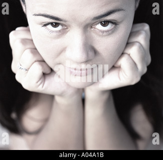 Portrait of a young woman resting her head on her hands looking at the camera Stock Photo