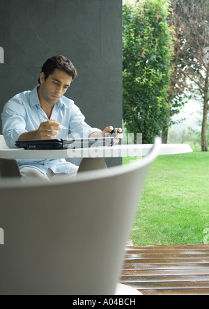 Man sitting at table outdoors, working Stock Photo