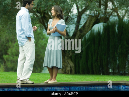 Man and woman talking by side of pool Stock Photo