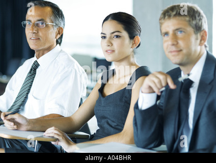 Businesspeople sitting holding, looking attentively out of frame Stock Photo