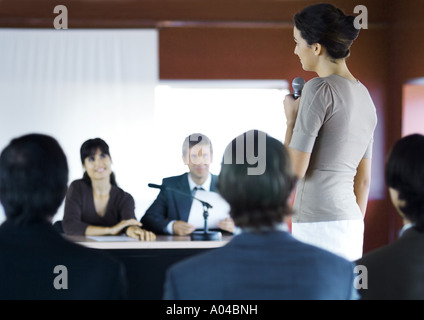 Businesspeople in seminar, one woman standing with microphone Stock Photo