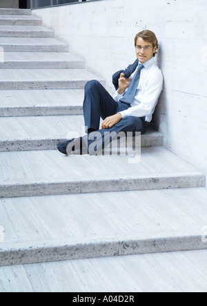 Businessman sitting on steps, smiling Stock Photo