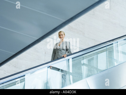 Businesswoman going down escalator Stock Photo