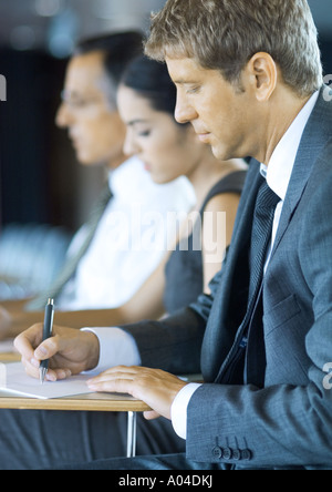 Executives sitting in seminar, taking notes Stock Photo