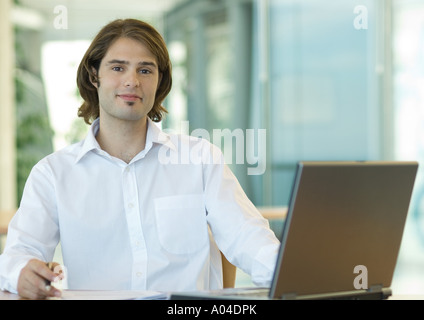 Young businessman sitting at desk, smiling at camera Stock Photo