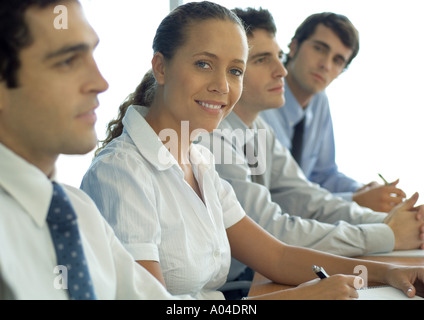 Business associates sitting at table, woman smiling at camera Stock Photo