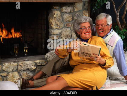 Healthy senior retired couple at home doing crossword puzzle by fireplace Stock Photo
