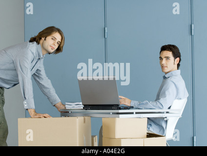 Businessmen working at table top supported by cardboard boxes Stock Photo