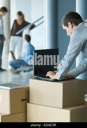 Businessman using laptop on cardboard box Stock Photo
