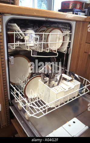 Dishwasher white goods electric domestic kitchen washing up machine close up clean crockery & cutlery in trays inside view with door open England UK Stock Photo