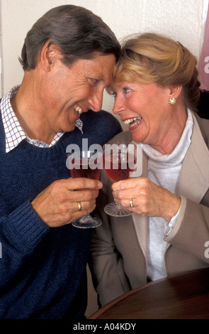 Happy romantic middle aged/mature couple congratulating each other with a glass of wine Stock Photo