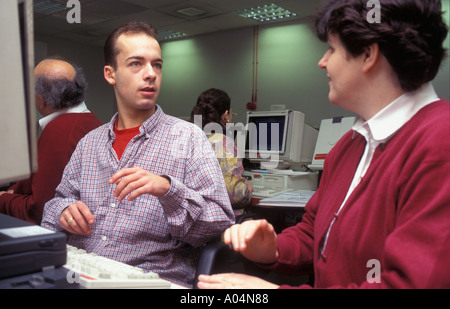 Deaf teacher working with hearing impaired adult students on computers. Stock Photo